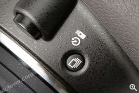 過片模式按鈕設在鏡頭釋放鍵下方。